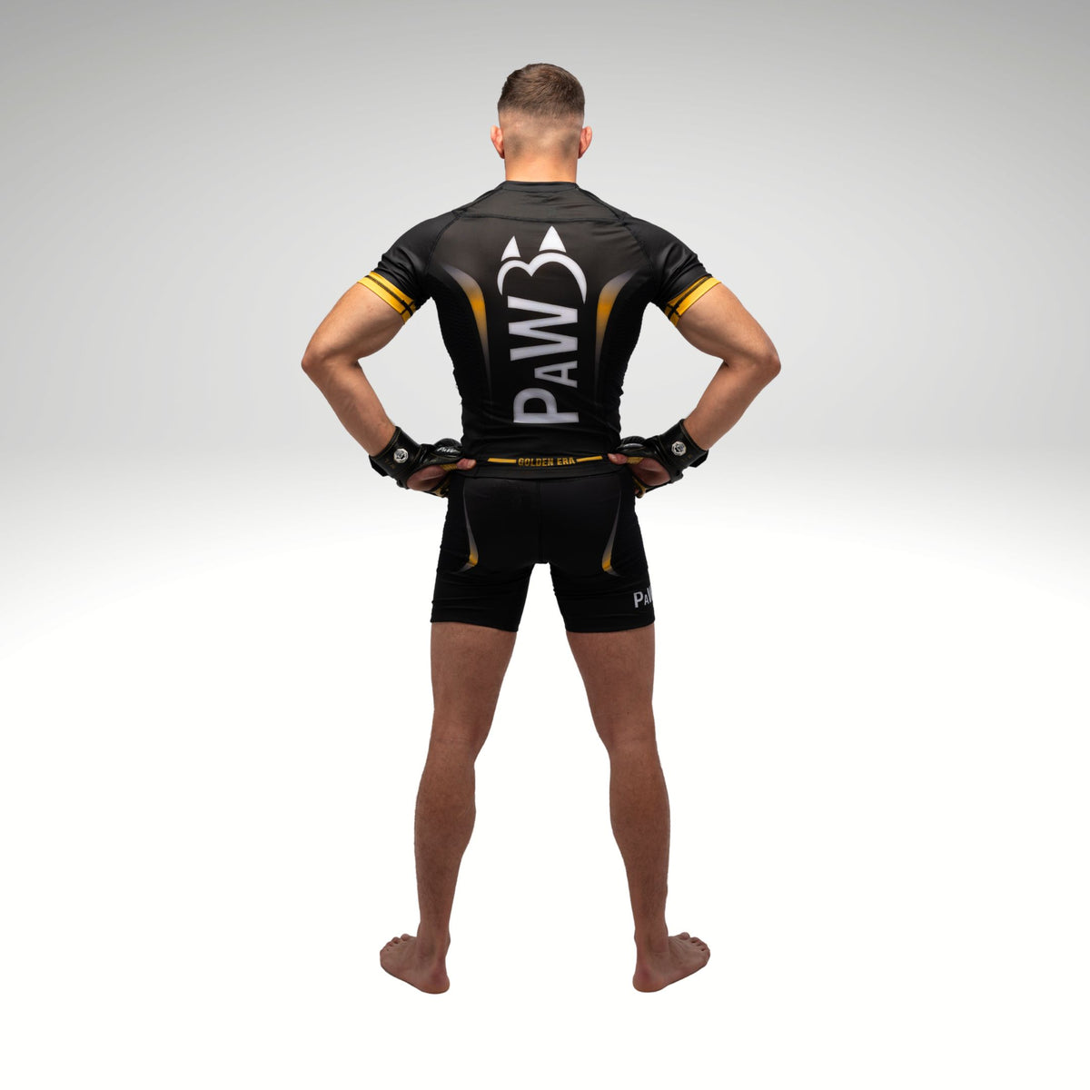 Rückenansicht eines MMA Kämpfers mit PAW Compression Shirt und MMA Handschuhen in Schwarz und Gold